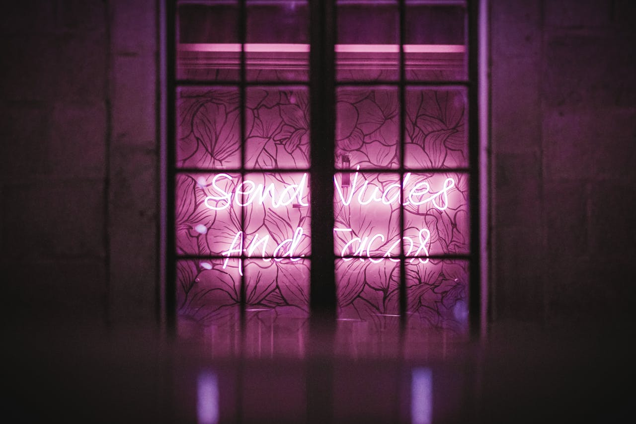 Bright pink neon lighting behind a decorative window frame adds an urban artistic touch.