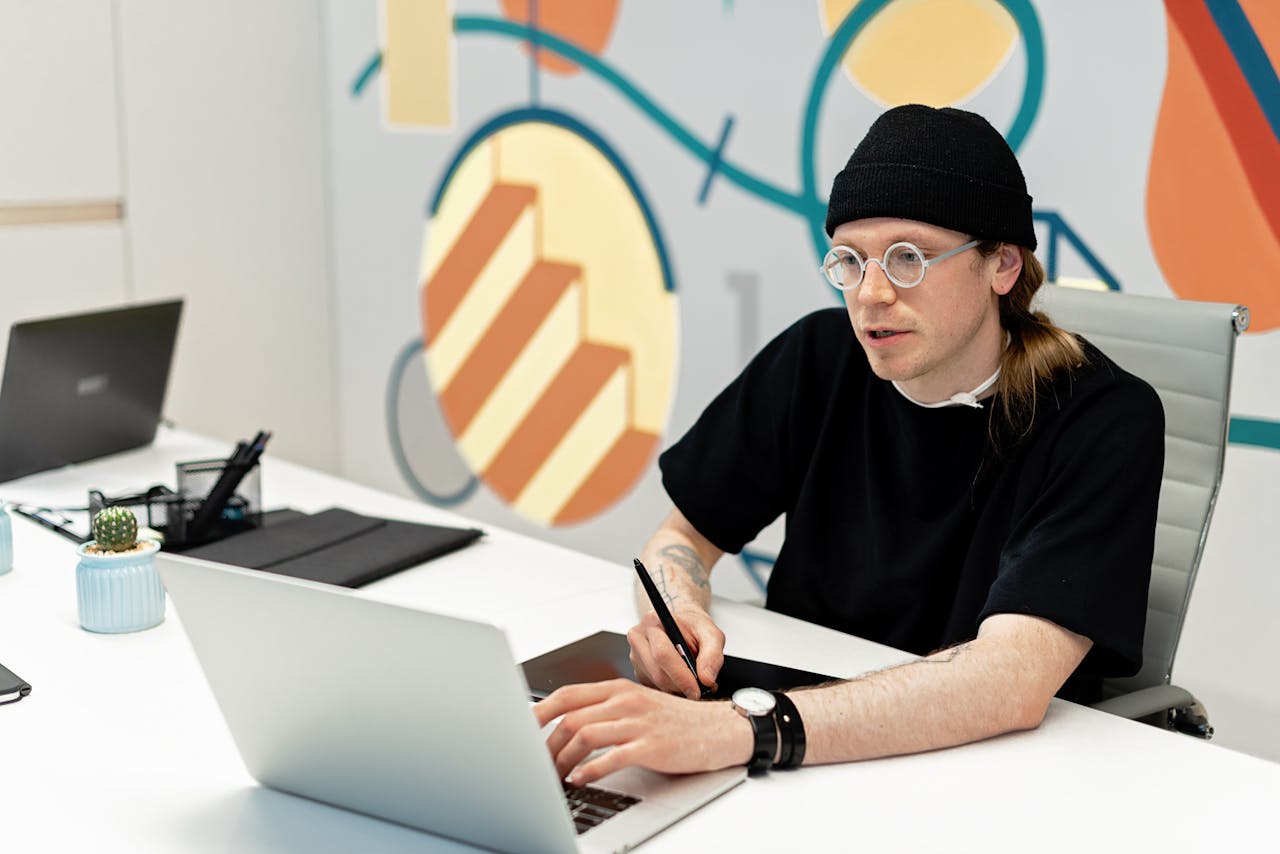 Young man working with laptop and tablet in a creative office space.
